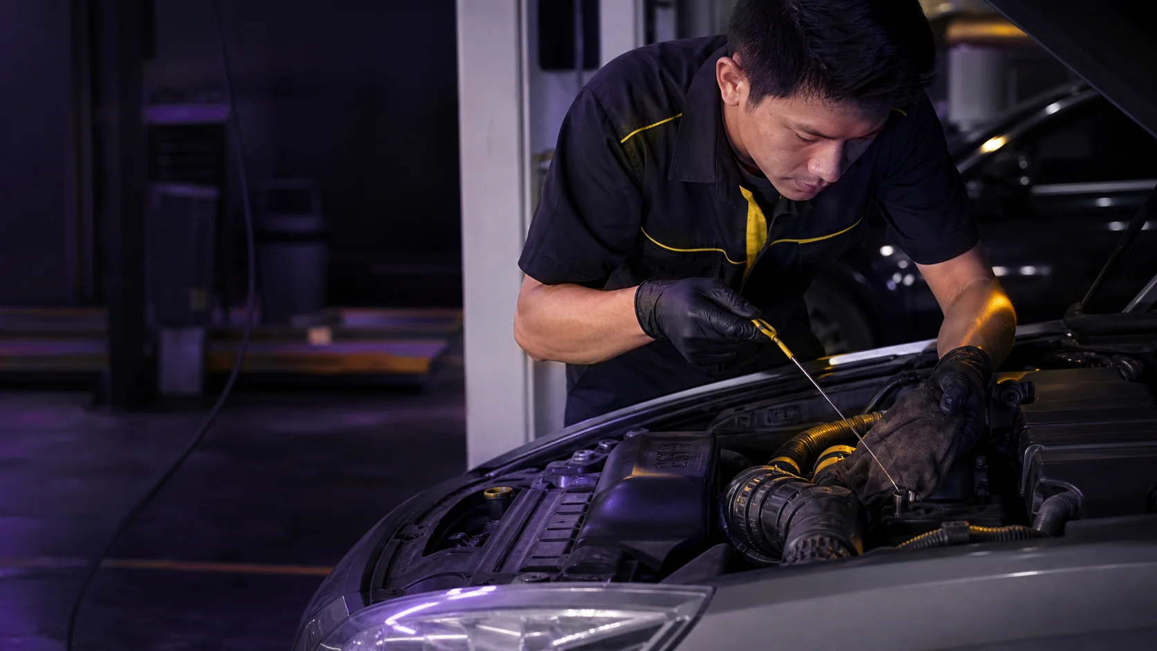 Technician checking engine oil during car service in a Kuantan workshop